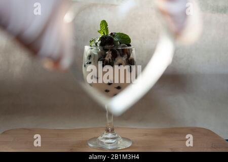 Kalter Schweißbecher mit bluebeeren naturweißem Joghurt und frischen Minzblättern, umrahmt von einem zuckerfreien Gourmet-Dessert aus Metall in Mexiko-Stadt Stockfoto