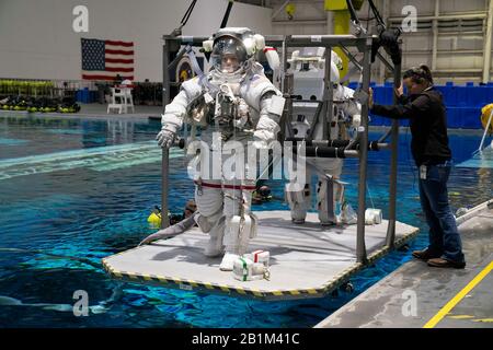 Ein Oberleitungskran senkt die Astronauten Anne C. McClain und Zena Cardman für das Schwerelosigkeitstraining in den Neutral Buoyancy Lab der NASA. Der 6,2 Millionen Liter fassende Pool enthält eine Verspottung der Internationalen Raumstation (ISS) in Houston. Stockfoto