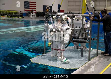 Ein Oberleitungskran senkt die Astronauten Anne C. McClain und Zena Cardman für das Schwerelosigkeitstraining in den Neutral Buoyancy Lab der NASA. Der 6,2 Millionen Liter fassende Pool enthält eine Verspottung der Internationalen Raumstation (ISS) in Houston. Stockfoto