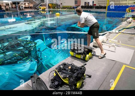 Ein Rettungstaucher der NASA bereitet seine Ausrüstung vor, bevor sie die Astronautin Anne C. McClain im Neutral Buoyancy Lab der NASA in Houston begleitet, während sie neutrales Auftriebstraining unterzieht. Der 6,2 Millionen Liter fassende Pool enthält eine Verspottung der Internationalen Raumstation (ISS). Stockfoto