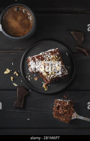 Ein Stück köstlicher Schokoladenkuchen in schwarzer Platte auf Holztischhintergrund, Nahaufnahme Stockfoto
