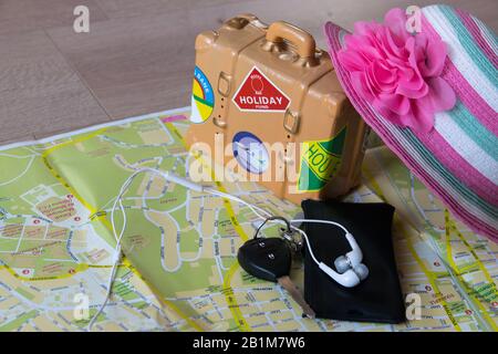 Die Karte, der Autoschlüssel, der rosafarbene Hut, die Kopfhörer für das Telefon sind für eine Sommerreise nach Spanien notwendig. Reisetongs auf Holzgrund. Reisekonzept. Stockfoto