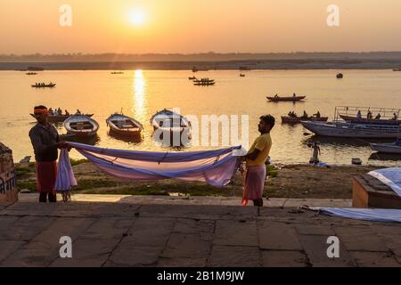 Indische Männer trocknen Kleidung in Ghats, nachdem sie in heiligem Wasser des Flusses Ganga bei Sonnenaufgang gewaschen wurden. Varanasi. Indien Stockfoto