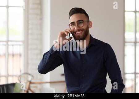 Ein tausendjähriger Unternehmer aus dem mittleren Osten, der im Büro telefoniert Stockfoto