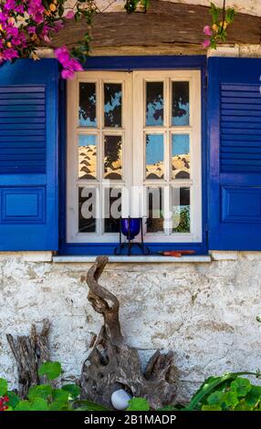 Ein attraktives schickes Fenster mit Schminkfenster in einer weiß getünchten Wand auf der griechischen Insel korfu in griechenland. Stockfoto