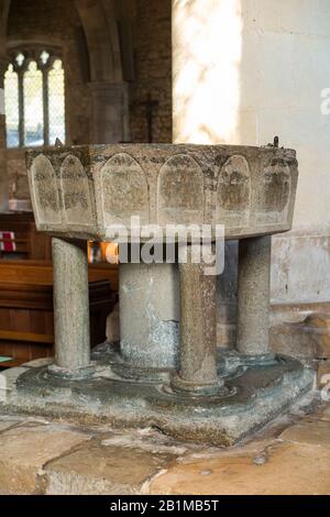 Achteckiges, aus Purbeck-Marmor geschnitztes, steinernes, spätnormannisches Taufbecken aus dem 12. Jahrhundert im Inneren der Kirche Bosham Holy Trinity. Bosham, West Sussex. GROSSBRITANNIEN. (114) Stockfoto