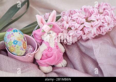 Osterrubbit in einem natürlichen Vogelnest mit Schokolade-Ostereiern neben e Frühlingsblume. Heim Ostern Feiertag Dekor Stockfoto