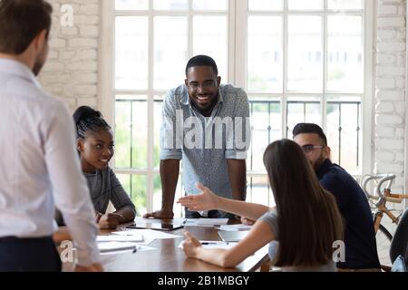 Multinationales, kreatives, positives Team, das an der Zusammenarbeit im Innenbereich denkt Stockfoto