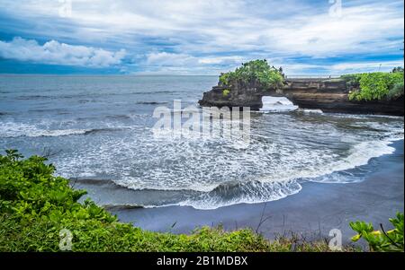 Batu Bolong-Tempel auf einer Felsenhalbinsel, die eine natürliche Brücke an der balinesischen Küste in der Nähe von Tanah Lot, Bali, Indonesien bildet Stockfoto