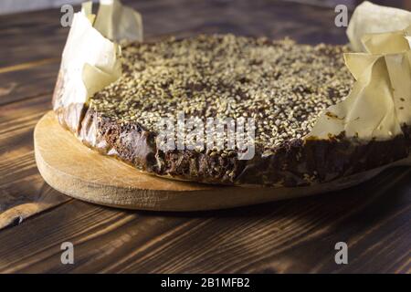 Frisch gebackenes, hausgemachtes Amaranth-Brot mit Sesamsamen bestreut. Heißes Brot in Backpapier, liegt auf dem Küchenblatt auf einem Holztisch. Nur von Stockfoto