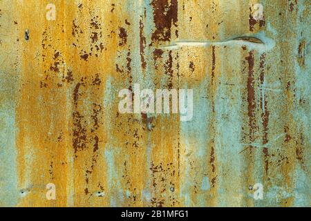 Alter Metallhintergrund. Textur der alten, getrockneten grüngelben Farbe auf einer rostigen Metalloberfläche. Stockfoto