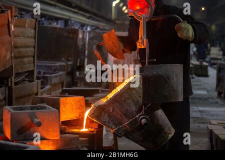 Industrieller Kühlguss. Das Verfahren zum Ausfüllen von Gussform mit geschmolzenem Metall aus Pfanne. Stockfoto