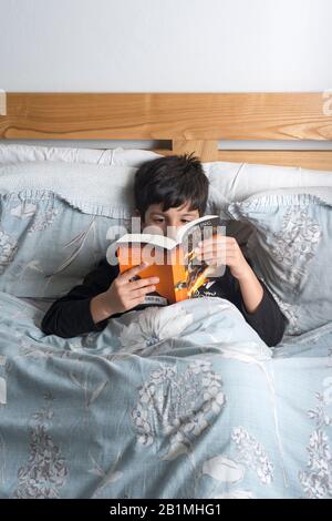 Young Boy liest Harry Potter Buch im Bett,.UK Stockfoto