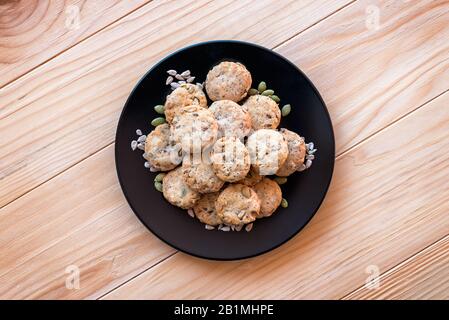 Gesalzene, knusprige, integrierte Cracker mit Sonnenblumen- und Kürbiskernen in einer schwarzen Platte auf einem Holztisch Stockfoto