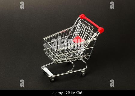 Leerer Spielzeug-Einkaufswagen mit grauem Hintergrund. Stockfoto
