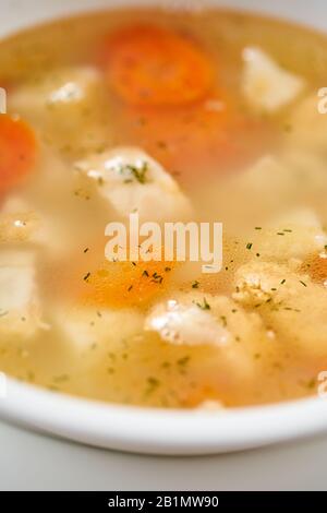 Fischsuppe in einem weißen Teller. Fischsuppe mit Gemüse, Sellerie in einer Tasse für die Brühe. Pike Barch und Lachs. Platte auf Holztisch. Restaurant-Menü Stockfoto