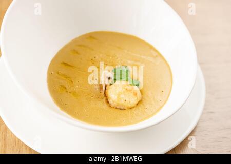 Fischsuppe in einem weißen Teller. Fischsuppe mit Gemüse, Sellerie in einer Tasse für die Brühe. Pike Barch und Lachs. Platte auf Holztisch. Restaurant-Menü Stockfoto