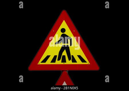 Schild für Fußgänger, die auf der Straße spazieren, gelb-rotes Brett mit schwarzem Hintergrund Stockfoto