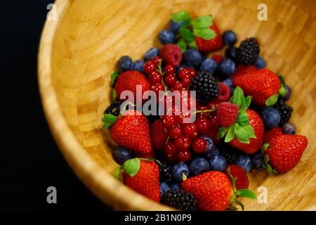 Frisches Beeren Obst in Holzschale enthält Erdbeere, Himbeere, blaue Beere, schwarze Beere usw. Stockfoto