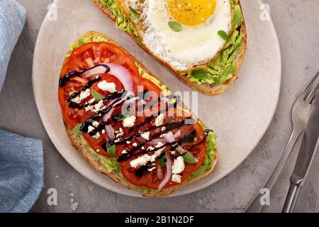 Avocado-Toast mit gebratenem Ei und Erbstück Tomaten Stockfoto