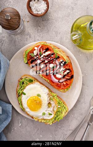 Avocado-Toast mit gebratenem Ei und Erbstück Tomaten Stockfoto