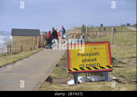 Milford-on-Sea, Großbritannien, 26. Februar 2020. Fußgänger nähern sich dem geschlossenen Abschnitt des Fußweges, auf dem Strandhütten in ein Sinkloch gerutscht sind, das sich nach starken Wellen gebildet hat, die Schäden an der Küstenmeerabwehr in der Nähe von Milford-on-Sea in Hampshire, Großbritannien Verursachen. In Den Letzten Längeren Phasen schwerer Stürme und schlechter Wetterbedingungen sind weite Teile der britischen Inseln betroffen. Stockfoto