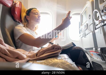 Legere junge Frau frischer während des Flugzeuges auf. Reisender, die im kommerziellen Flugzeug fliegen und in der Economy-Passangerkabine sitzen. Stockfoto