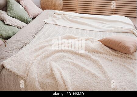 Kuschelig flauschige Pastelltöne auf einem großen hellen Bett im Boho-Stil Stockfoto