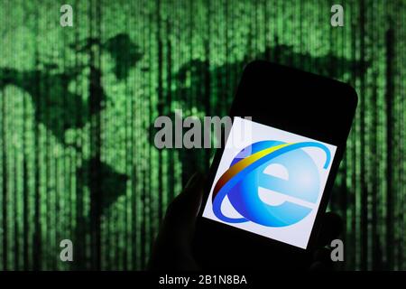 Internet Explorer-Webbrowserlogo wird auf dem Smartphone-Bildschirm angezeigt, wobei die Matrix-ähnliche Weltkarte im Hintergrund verschwommen zu sehen ist Stockfoto