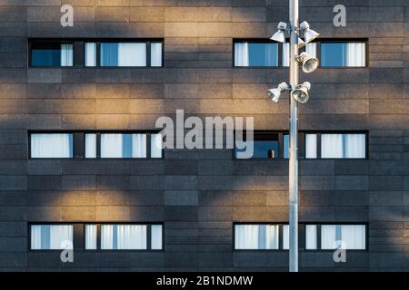 Streetlight und schwarze Fassade eines städtischen Gebäudes mit langen horizontalen Fenstern Stockfoto