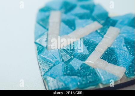 Herzform aus blauem Keramikmosaik in kleinen Blautönen mit weißen Buchstaben VL auf weißem, sauberem Hintergrund Stockfoto