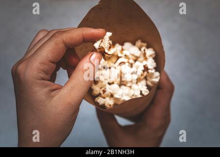 Frau, die einen Papierkegel voller Popcorn hält. Draufsicht. Ansicht von oben Stockfoto