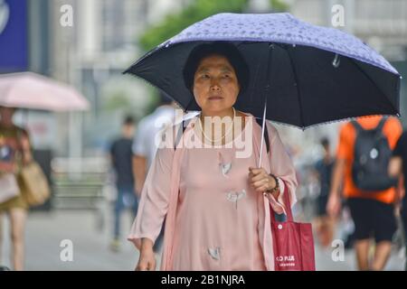 Wuhan: Chinesische Frau schützt vor der Sonne mit einem Regenschirm an der Ausfahrt der U-Bahn-Station Chuhe Hanije, Zhong bei Lu Street. China Stockfoto