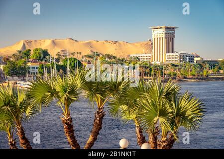 Assuan, Ägypten - Movenpick Hotelgebäude am Ufer des Nils mit Palmen im Vordergrund Stockfoto