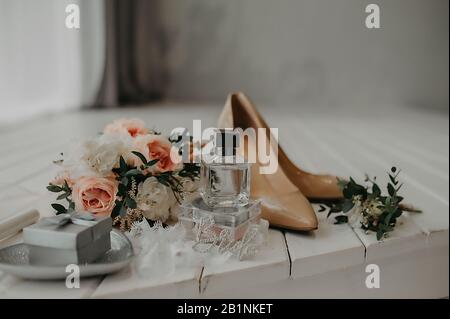 Accessoires für die Hochzeit: Beige Lacklederschuhe, Parfüm und ein süßer, stylischer Blumenstrauß aus kleinen Rosen in einem hellen Farbton Stockfoto