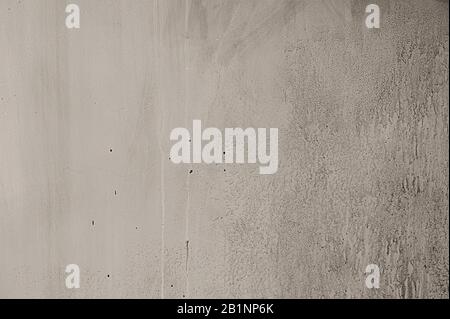Weiße Betonwandstruktur mit Rissen und Unebenheiten und Spuren von Fließwasser Stockfoto