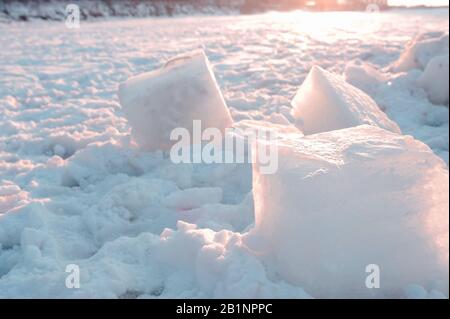 Groß von Menschen gesägte Eiswürfel liegen auf dem Schnee und auf dem gefrorenen Meer bei Sonnenuntergang Stockfoto