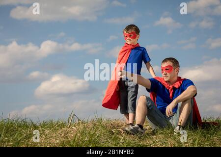 Vater und Sohn spielen Superhelden in der Tageszeit. Leute, die Spaß im Freien. Konzept der freundlichen Familie. Stockfoto