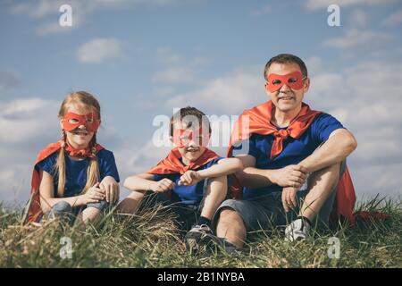 Vater und Kinder spielen Superhelden in der Tageszeit. Leute, die Spaß im Freien. Konzept der freundlichen Familie. Stockfoto