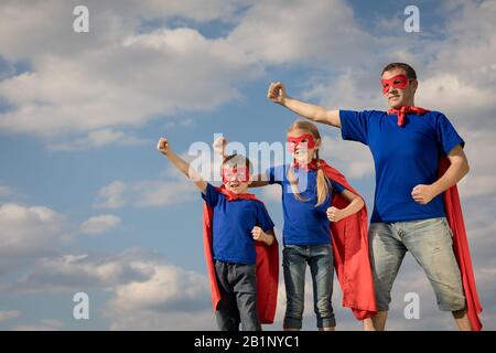 Vater und Kinder spielen Superhelden in der Tageszeit. Leute, die Spaß im Freien. Konzept der freundlichen Familie. Stockfoto