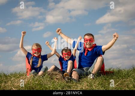 Vater und Kinder spielen Superhelden in der Tageszeit. Leute, die Spaß im Freien. Konzept der freundlichen Familie. Stockfoto