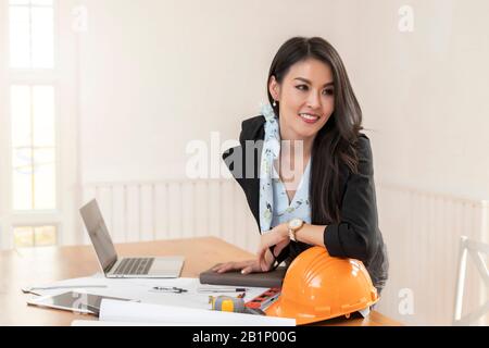 Weibliche Architektin arbeitet an ihrem Schreibtisch mit Blueprint Architektenprojekt im Vintage-Büro. Stockfoto