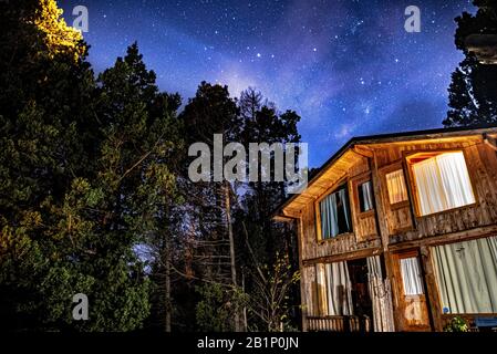 Bariloche, ARGENTINIEN, 19. JUNI 2019: Außenansicht einer gemütlichen und entspannenden Holzhütte im Wald mit einem wundervollen Sternenhimmel Stockfoto