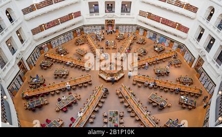 Blick vom 6. (Oberen) Stock auf die langen, strahlenden Schreibtische im La Trobe Reading Room der State Library of Victoria in Melbourne, Aust Stockfoto