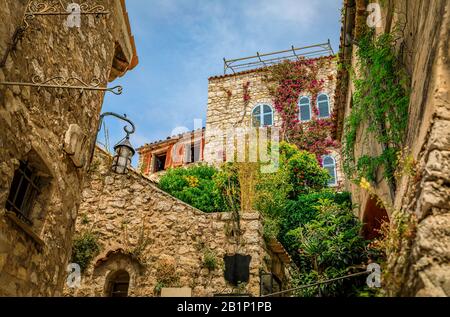 Steinaußenseite alter Gebäude mit Blumen in den Straßen von Eze Village, malerischer Mittelalterstadt in Südfrankreich entlang des Mittelmeers Stockfoto