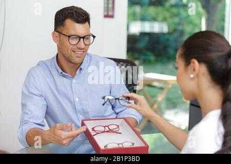 Augenoptiker, der die Rahmen für den Patienten vorschlägt, um es zu versuchen Stockfoto