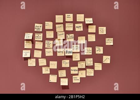 Weinrote Wand mit hängenden gelben Haftnotizen Stockfoto