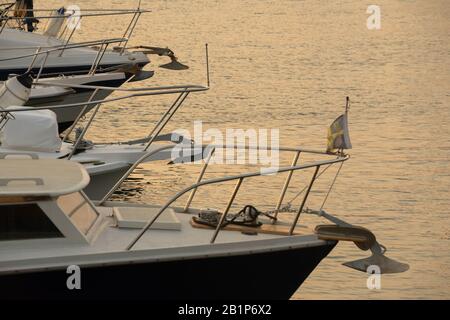 Orangefarbener Sonnenuntergang über dem Wasser mit Motoryachten auf der linken Seite des Bildes Stockfoto