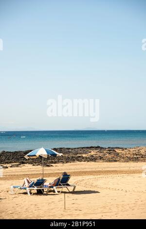 Zwei Personen genießen einen sonnigen Tag am Strand auf der Insel Lanzarote Kanarische Inseln Spanien. Stockfoto