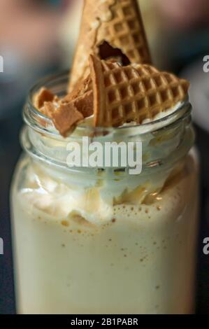 Nahaufnahme von kaltem Kaffee mit Schlagsahne und Waffelkonus Stockfoto